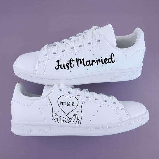 Baskets Stan Smith custom mariage blanches avec message “Just Married” et dessin de mains enlacées avec initiales M & K, personnalisables sur Air Force 1 ou baskets cuir blanches, création Sneakeaze Customs.
