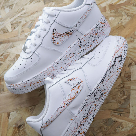 Air Force 1 custom effet peinture éclaboussée noir et orange, création sur-mesure peinte à la main, sneakers Nike personnalisées exclusives Sneakeaze.
