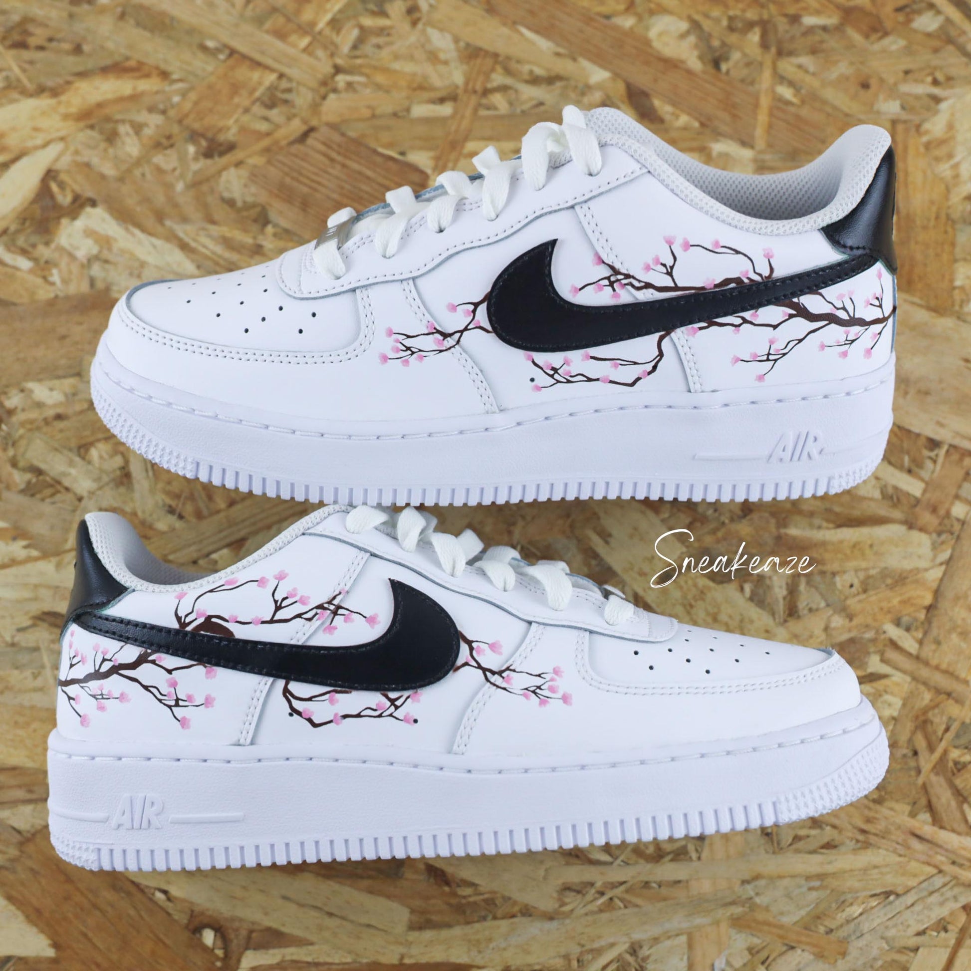 Baskets Air Force 1 custom cherry blossom avec swoosh et talon peint en noir et dessin fleurs de cerisiers peint à la main sur les côtés extérieurs uniquement couleur rose pastel.