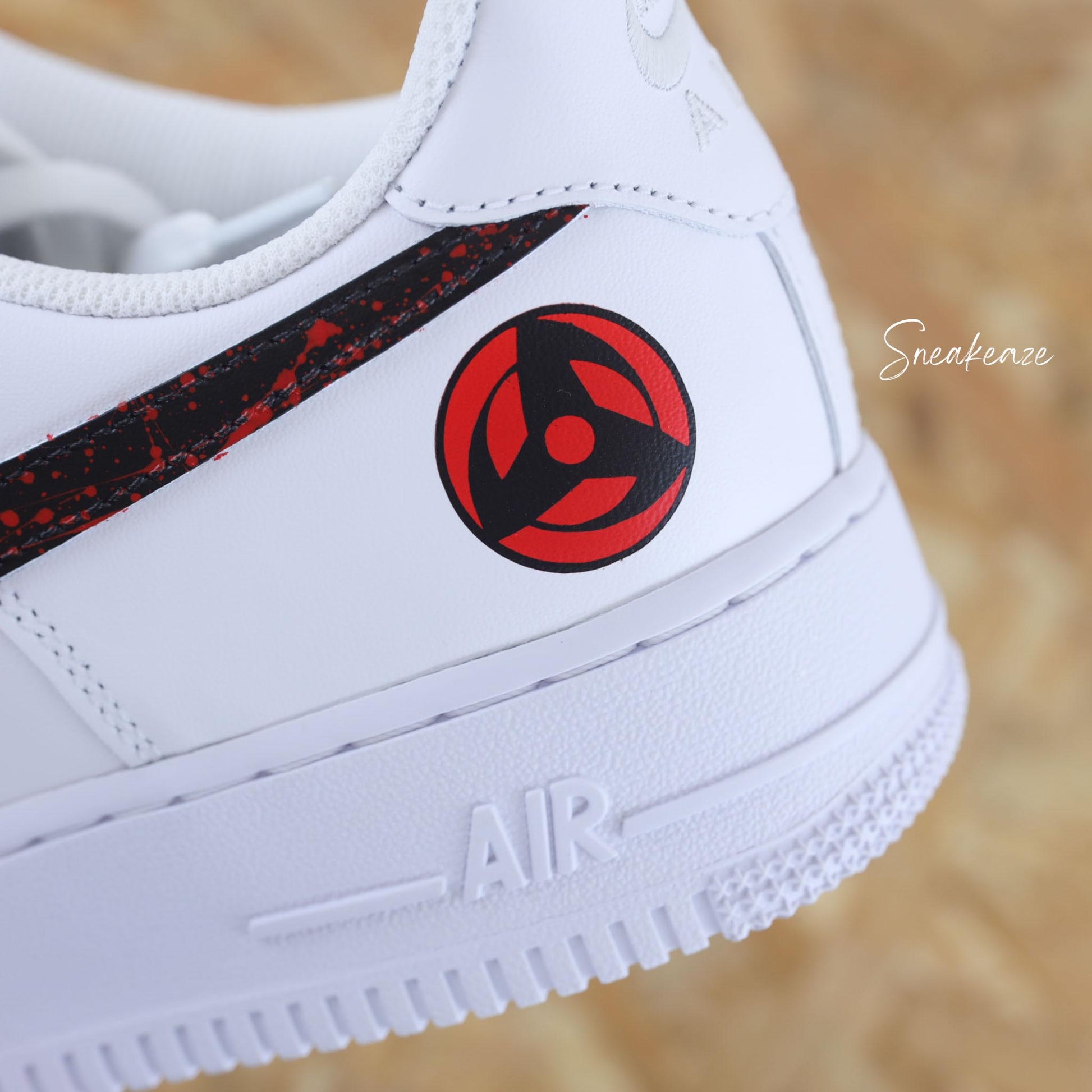 Nike Air Force 1 custom avec motifs Naruto sur les côtés extérieurs, swoosh noir et splash rouge intense — une paire unique pour les fans de manga et de sneakers.