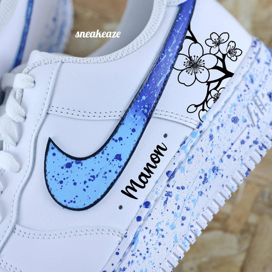 Baskets Nike Air force 1 custom motifs fleurs sur côtés extérieurs avec prénom. Signes Nike peints en dégradé bleu avec splash assortis sneakeaze customs