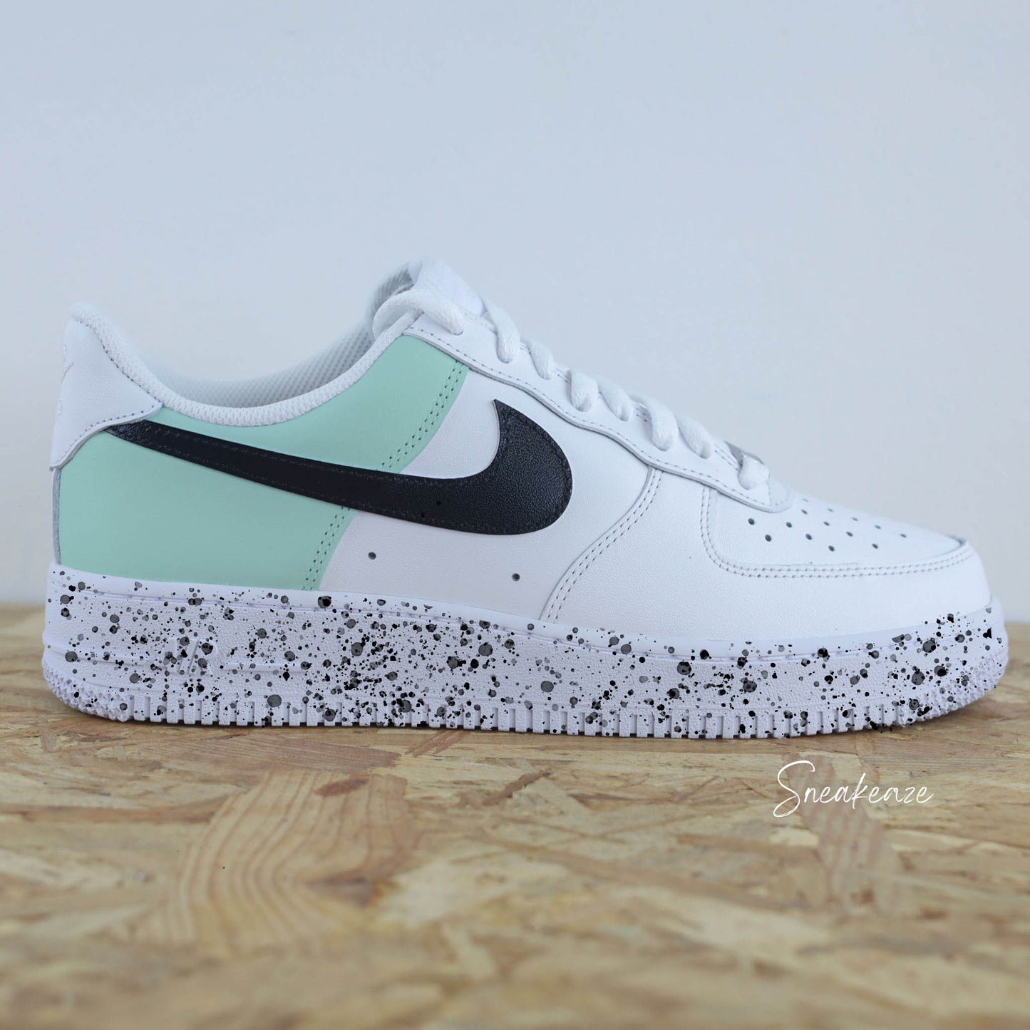 Basket Nike Air force 1 custom color block vert d'eau et noir. Signes Nike peint sur les 4 cotés en noir avec splash de peinture assortis sneakeaze custom