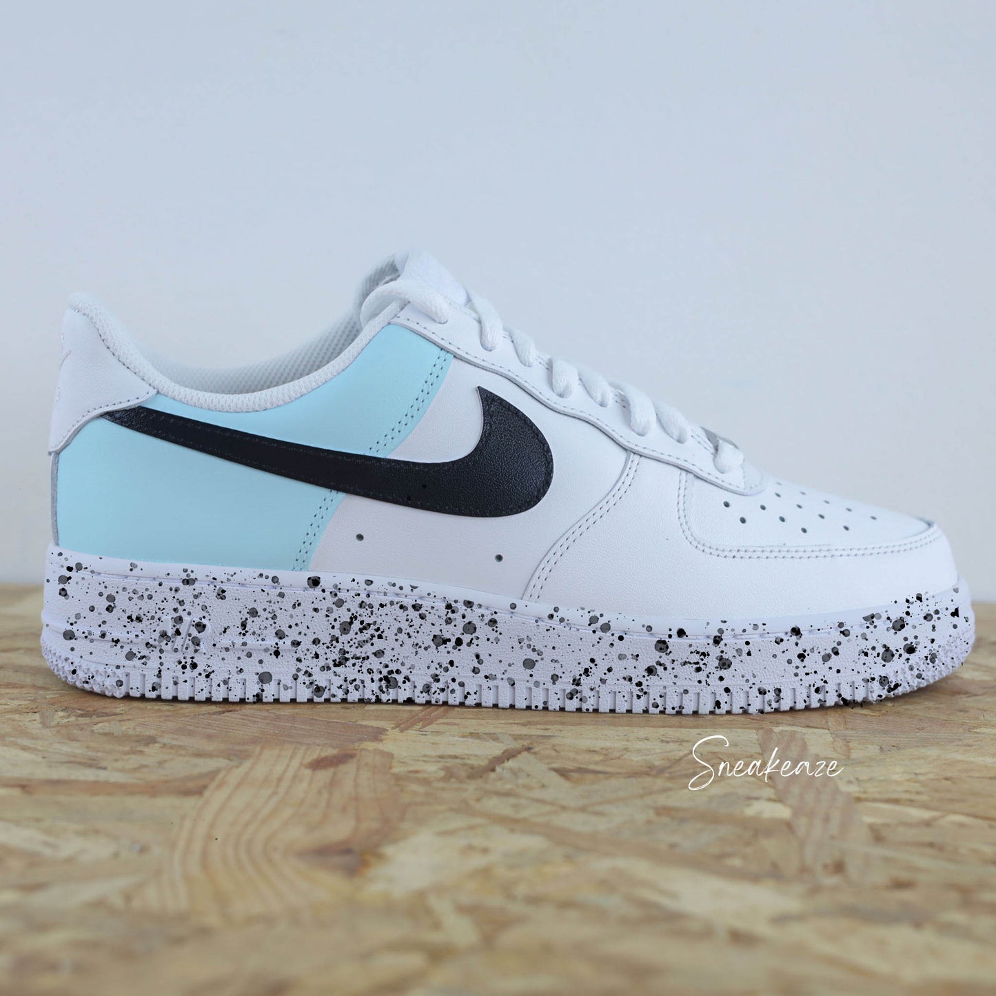 Basket Nike Air force 1 custom color block baby blue et noir. Signes Nike peint sur les 4 cotés en noir avec splash de peinture assortis sneakeaze custom