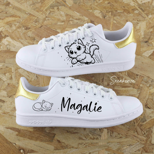 Baskets Adidas Stan Smith custom blanches avec dessin de chaton peint à la main et l'inscription du prénom pour enfant, le tout sur les côtés extérieurs. talon peint en doré