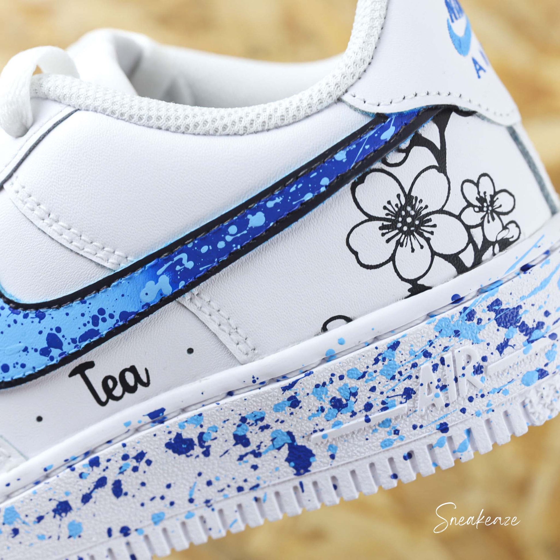 Baskets Nike Air force 1 custom motifs fleurs sur côtés extérieurs avec prénom. Signes Nike peints en dégradé bleu avec splash assortis sneakeaze customs