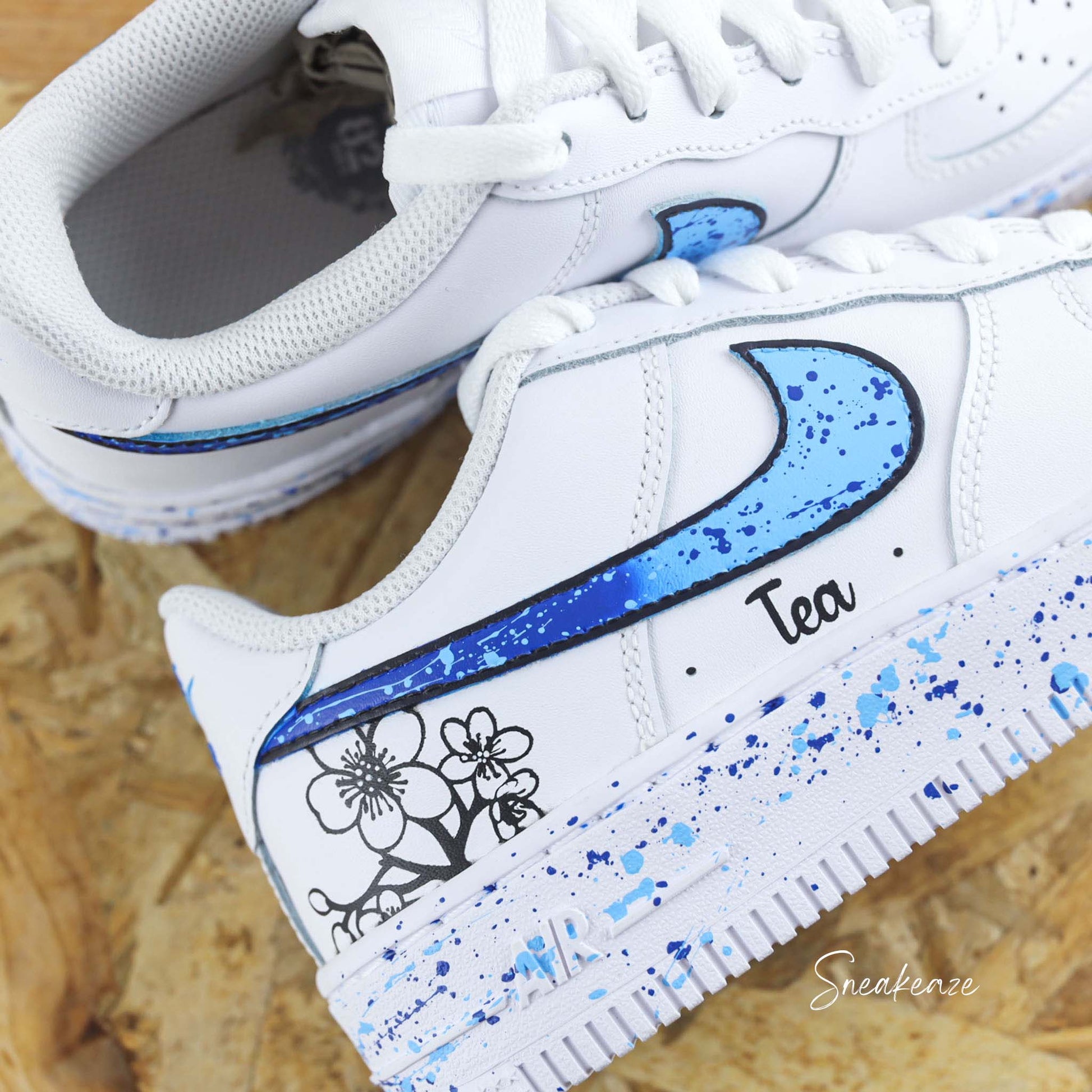 Baskets Nike Air force 1 custom motifs fleurs sur côtés extérieurs avec prénom. Signes Nike peints en dégradé bleu avec splash assortis sneakeaze customs