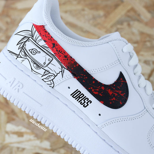 Baskets Nike Air force 1 custom motifs naruto sur côtés extérieurs. Signes Nike peints en dégradé rouge et noir avec splash assortis et prénom sous le sneakeaze custom