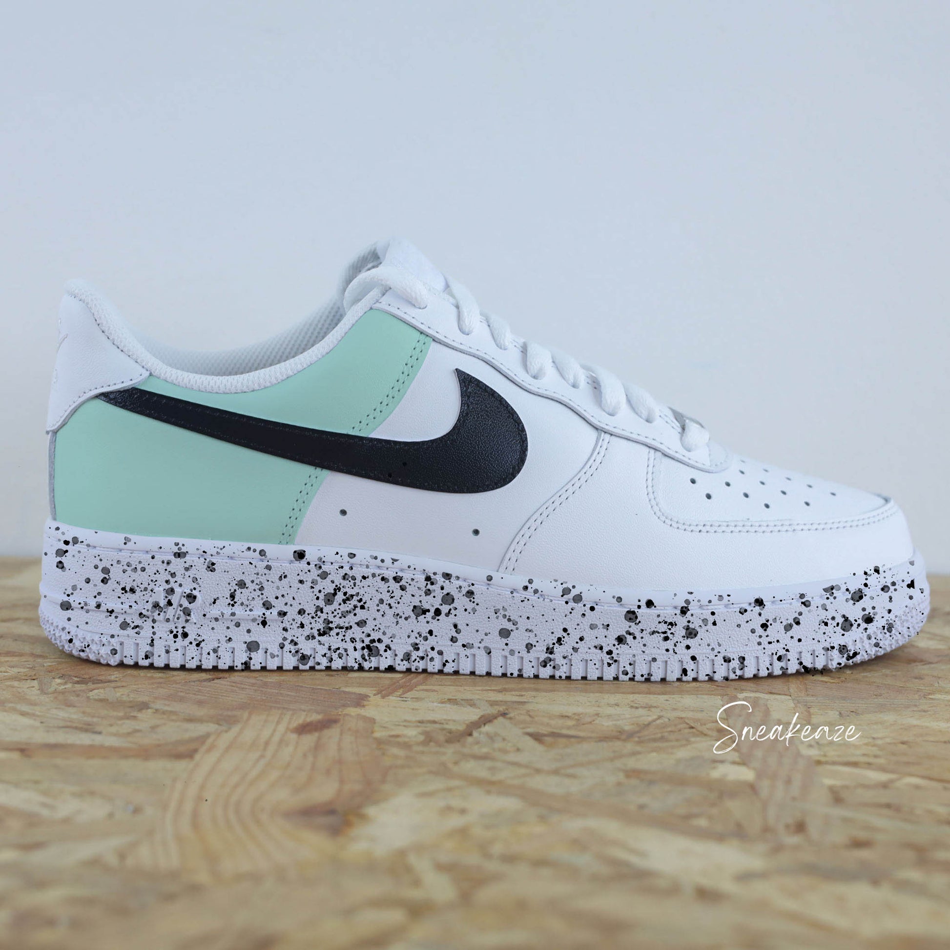 Basket Nike Air force 1 custom color block vert d'eau et noir. Signes Nike peint sur les 4 cotés en noir avec splash de peinture assortis sneakeaze custom