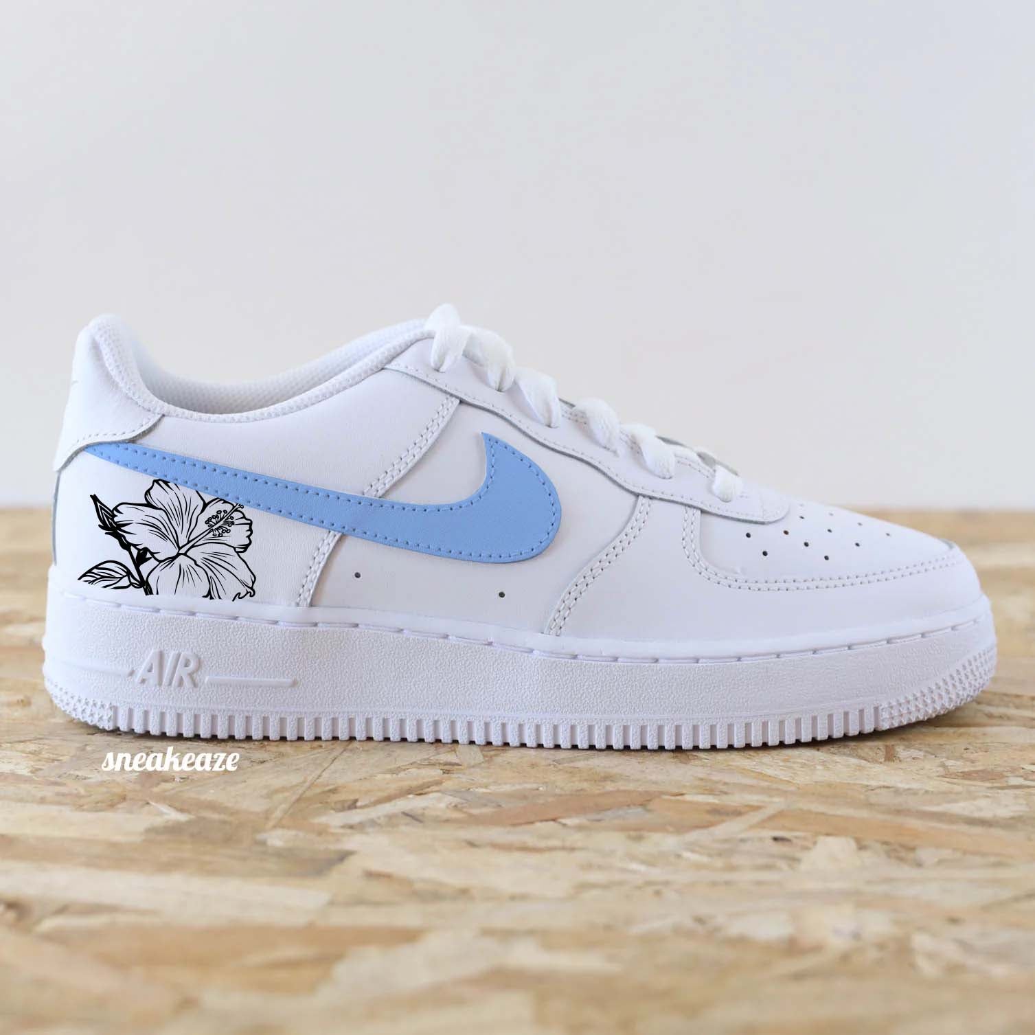 Baskets Nike Air Force 1 custom swoosh couleur unc blue pastel et dessin d'hibiscus sur les côtés extérieurs