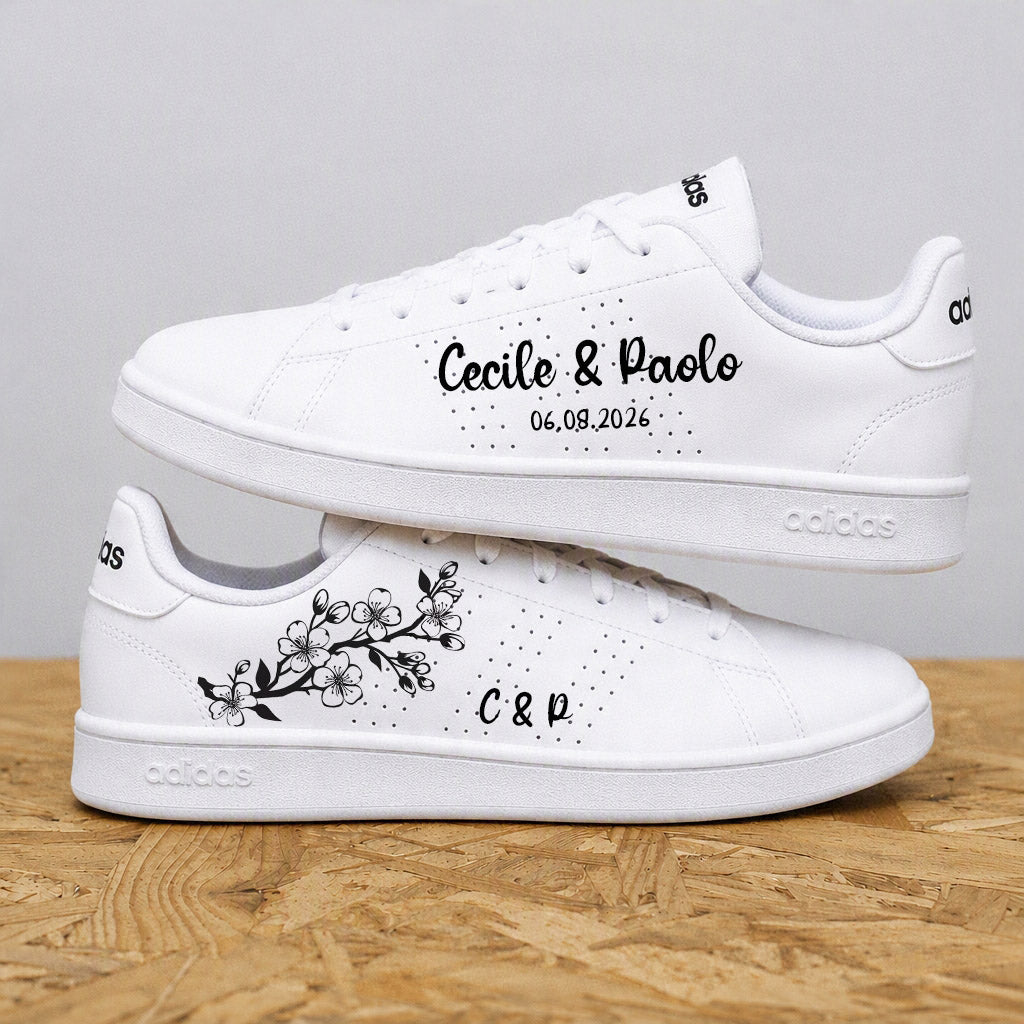Paire d'adidas de mariage personnalisées avec un motif floral de fleurs de cerisiers et les prénoms des mariés par Sneakeaze