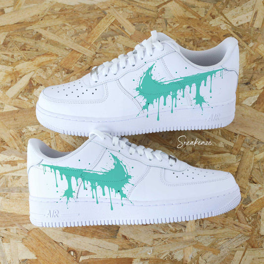 Chaussures Nike Air Force 1 custom street art avec un logo Nike drip vert turquoise en train de fondre et des éclaboussures.